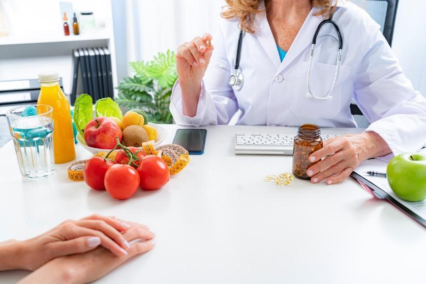 A doctor and patient at a table Description automatically generated